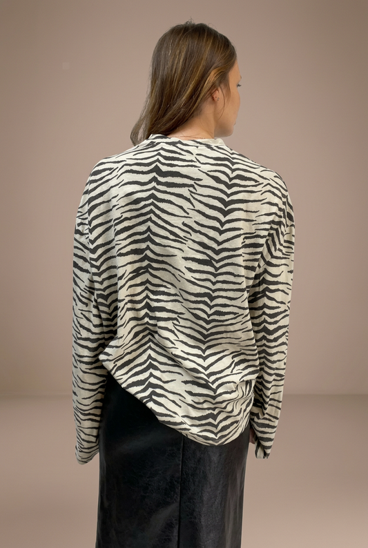 Maglia zebrata bianco panna e nero indossata, vista dietro su sfondo tortora da studio