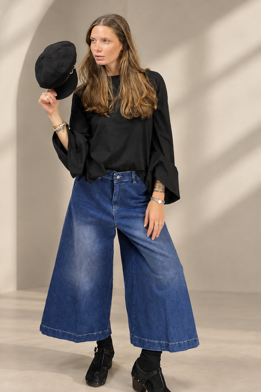 T-shirt Basic nera indossata su sfondo greige da studio