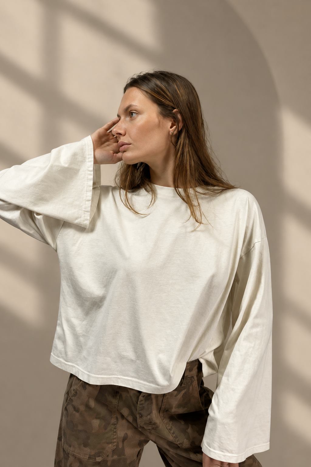 T-shirt Basic bianca, foto ravvicinata su sfondo greige da studio