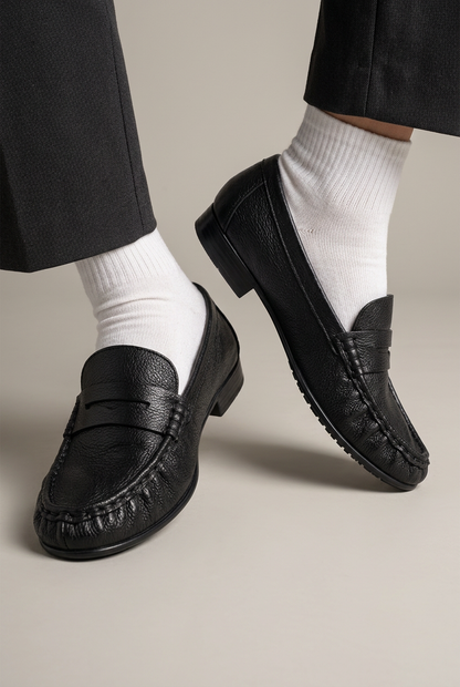 Mocassino 136 in nappa nera indossato con calzino bianco, primo piano su sfondo da studio