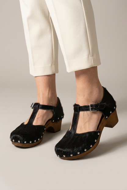 Zoccolo Heidy nero in cavallino indossato, primo piano con pantalone avorio e sfondo da studio