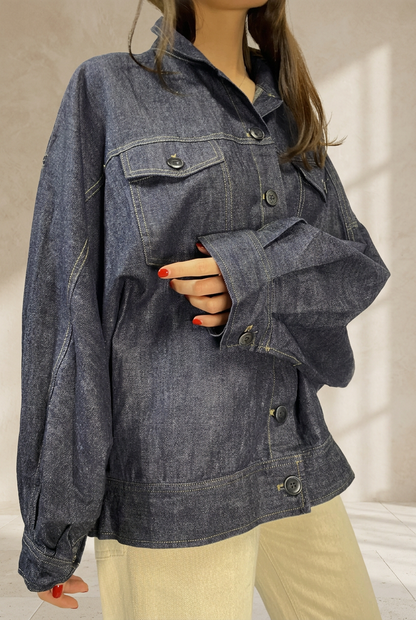 Giubbino 411 in denim scuro, dettaglio frontale su sfondo da studio color sabbia
