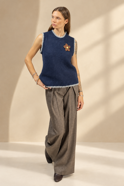 Gilet Cortina blu con fiore applicato, vista frontale su sfondo champagne da studio