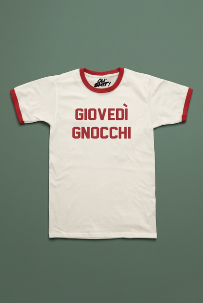 T-shirt Giovedì Gnocchi distesa su sfondo verde salvia, con bordi e scritta rossi